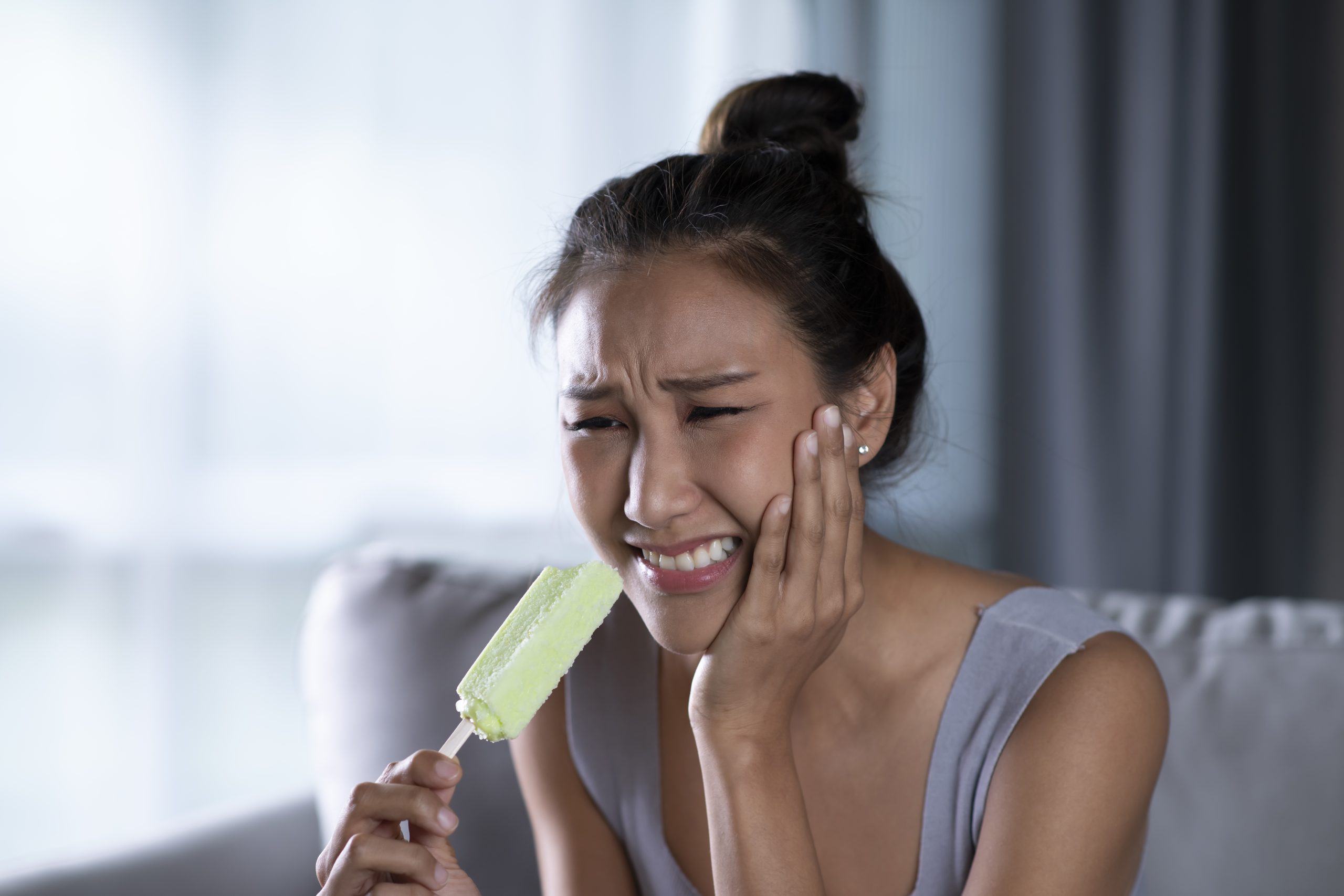 Mujer con sensibilidad dental a los alimentos fríos