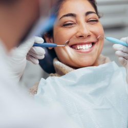 Over the shoulder view of a dentist examining a patients teeth in dental clinic. Female having her teeth examined by a dentist.