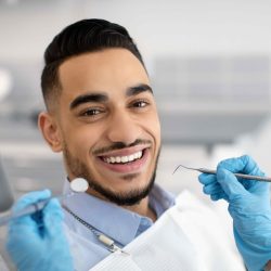 Portrait Of Happy Arab Man Sitting At Dentist Chair In Modern Clinic And Smiling At Camera, Middle Eastern Male Patient Enjoying Dental Treatment With Professional Stomatologist, Closeup Shot